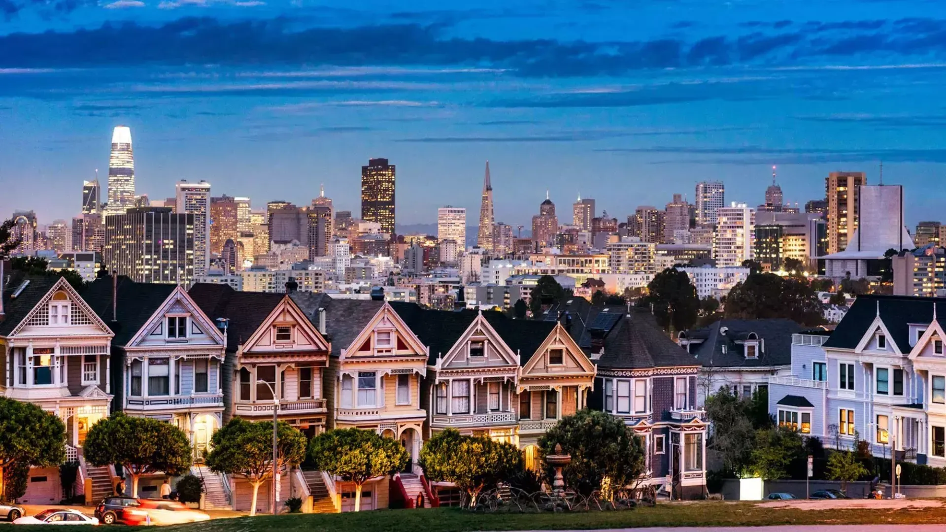 The famous Painted Ladies of Alamo Square are pictured before the San Francisco skyline at twilight.